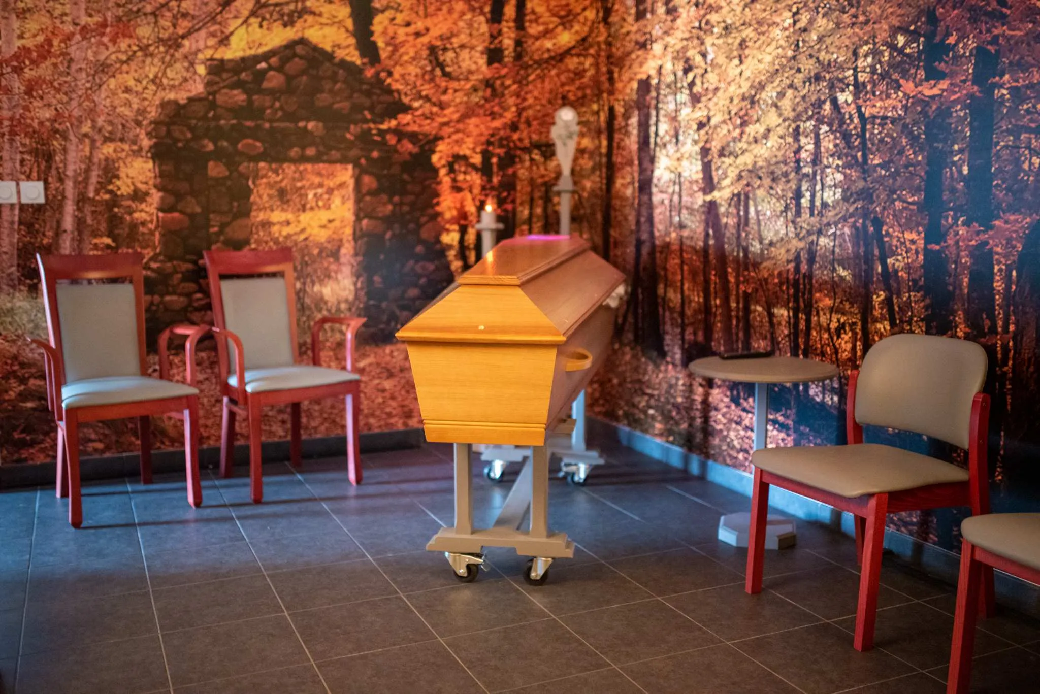 Salon de recueillement d'une chambre funéraire avec un cercueil en bois et des chaises