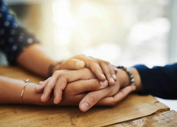 Mains serrées sur une table en signe de soutien et de réconfort